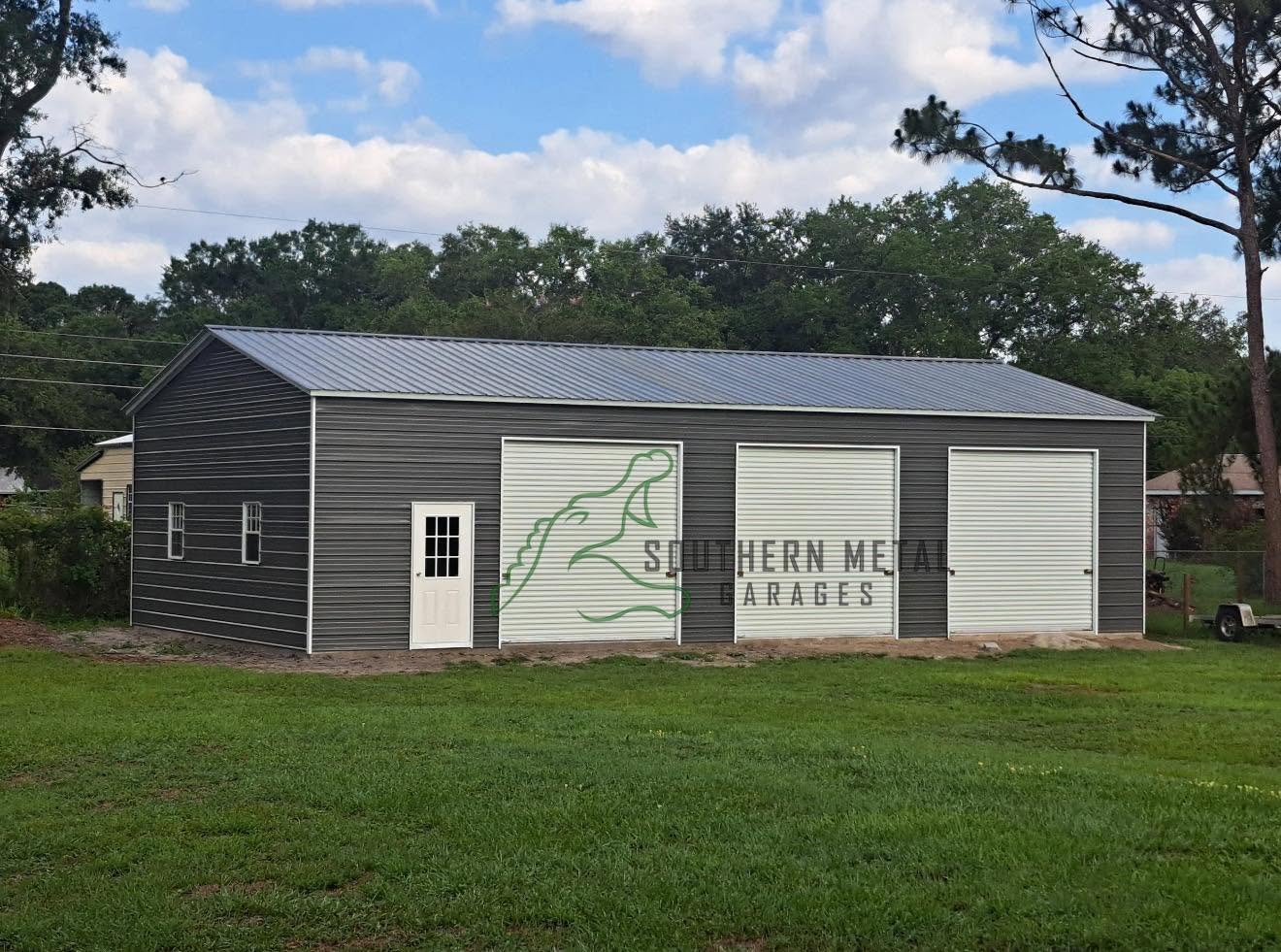 Gray three-bay metal garage with white doors built by Southern Metal Garages
